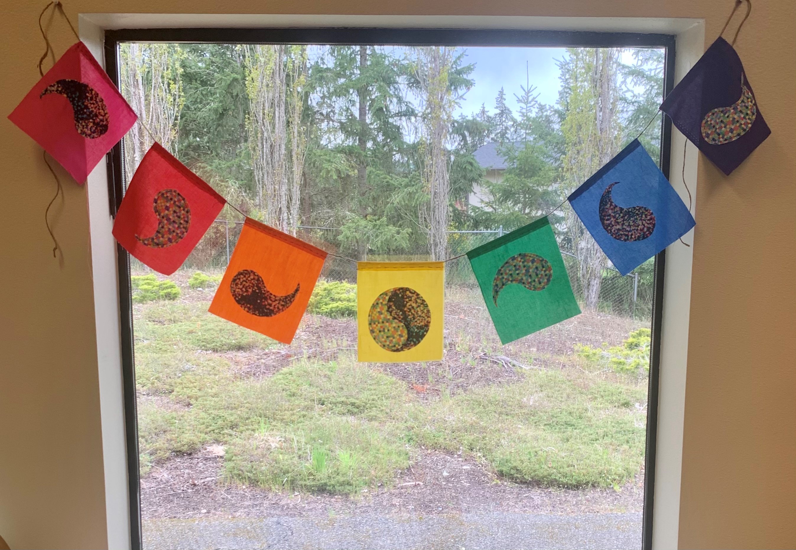 Color Rainbow Wish Flags hanging in a window.