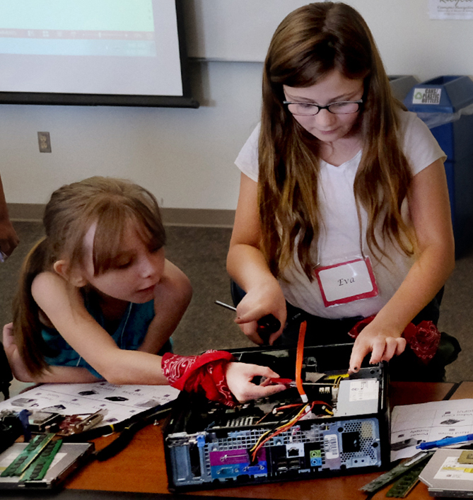 Image of two young girls taking apart a computer.