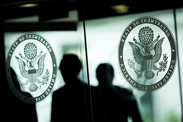 image of shadowed figures standing in front of the State Department seal.