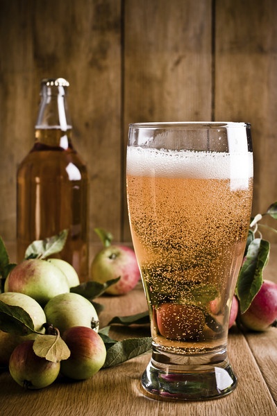 Image of a glass of cider surrounded by apples.