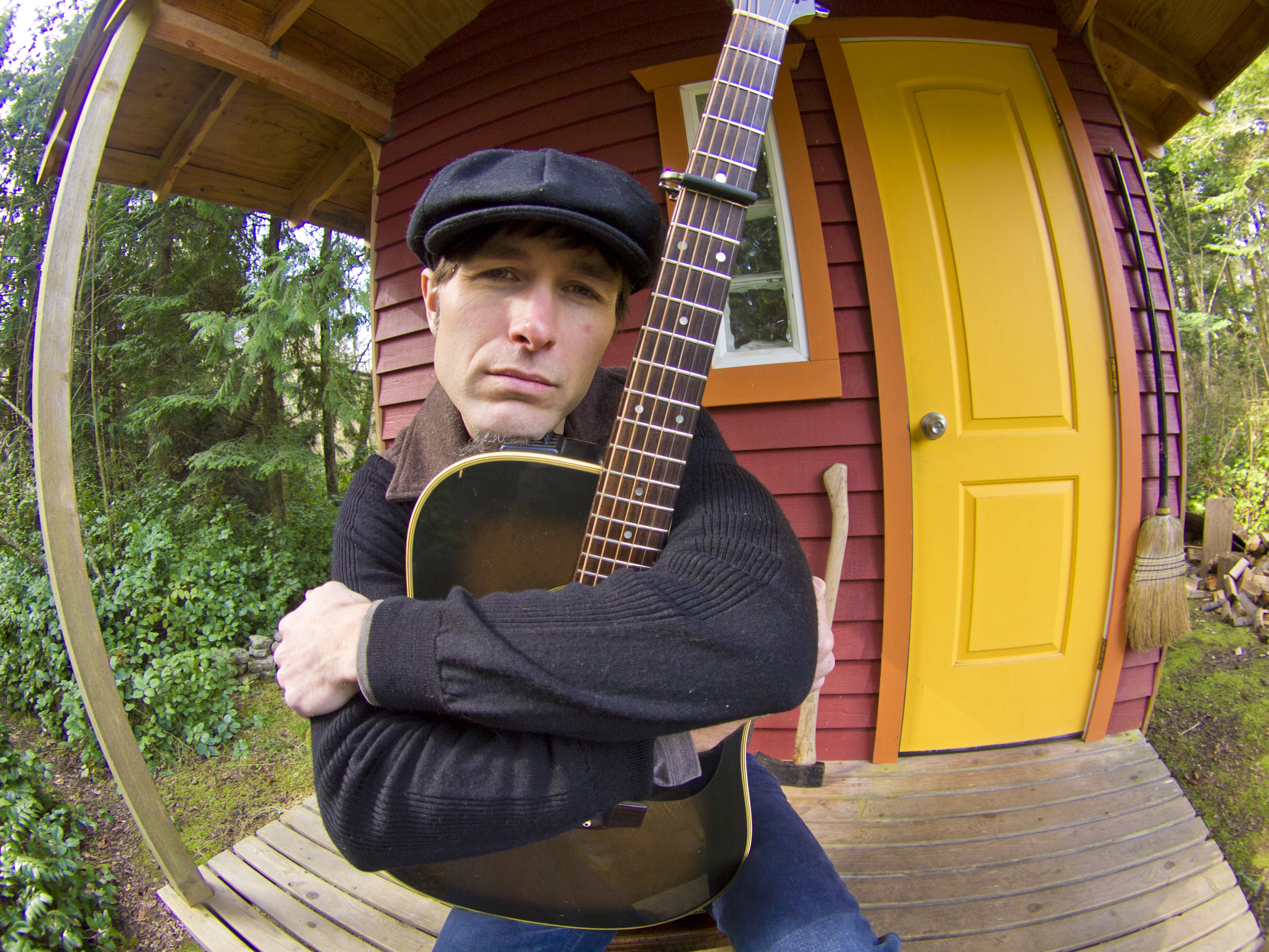Singer Keeth Apgar on a porch holding a guitar