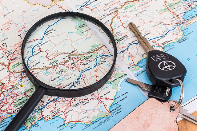 Magnifying glass and car keys sitting on a road atlas
