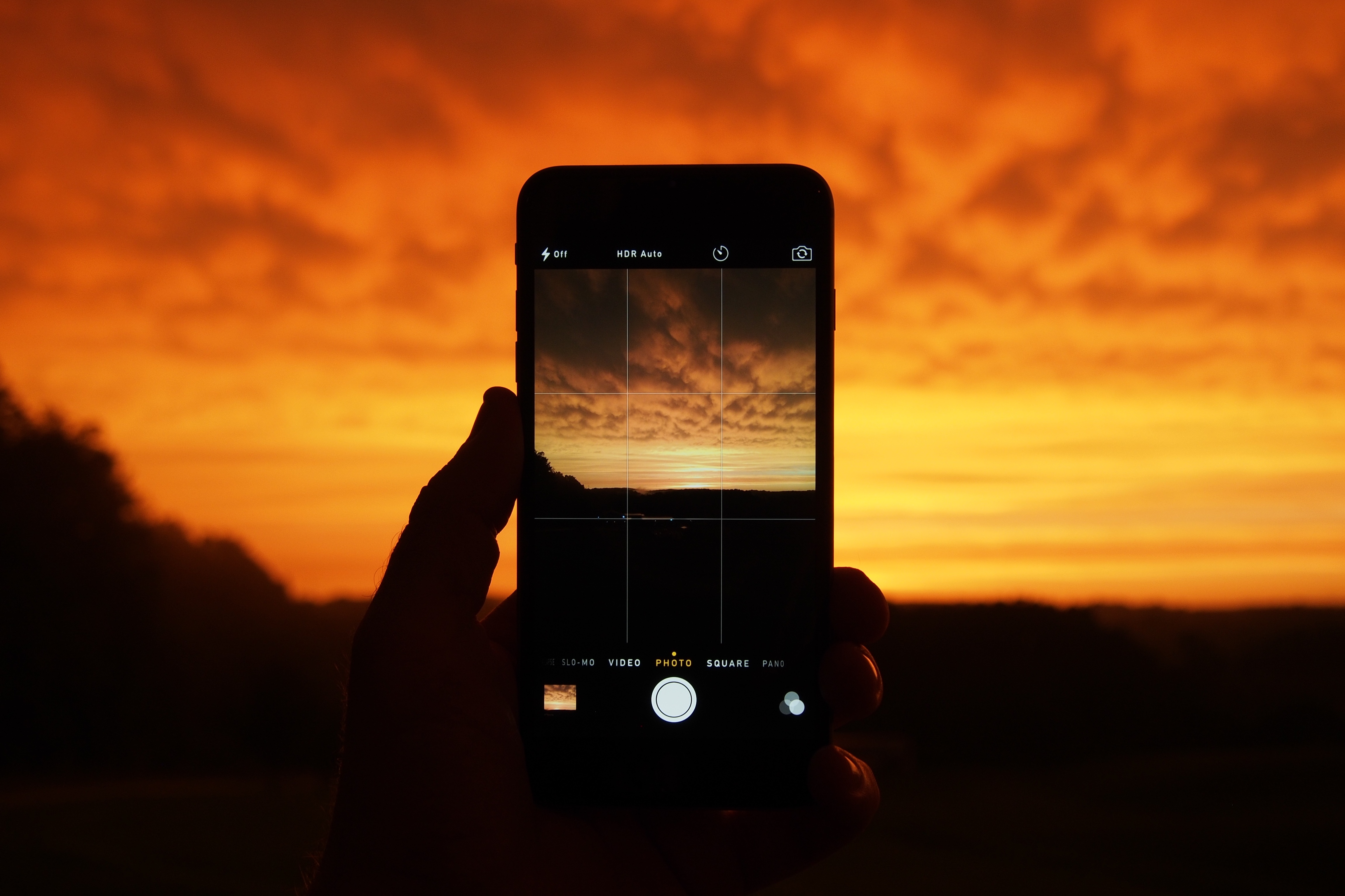 Mobile device taking photograph of a sunset.