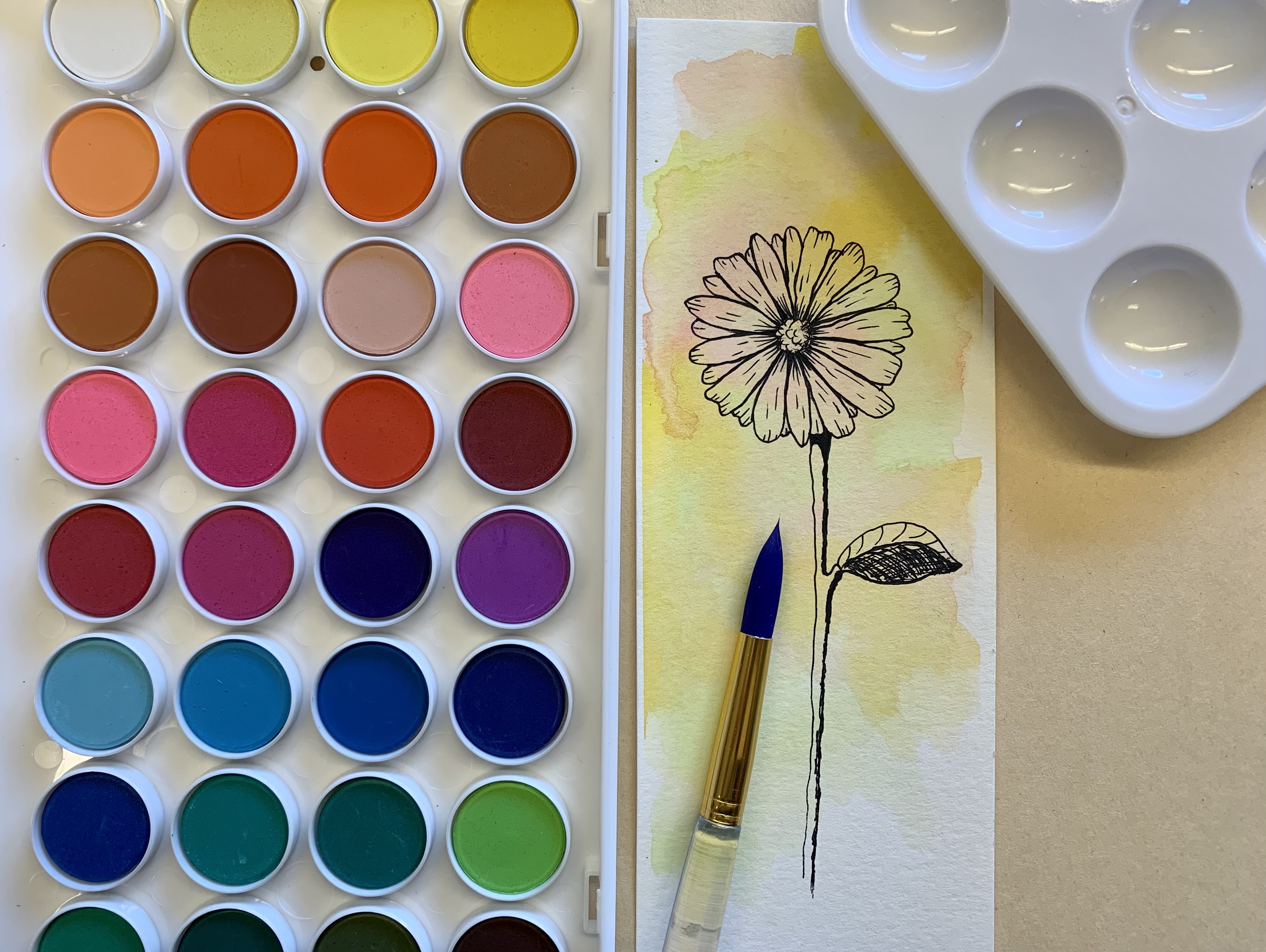 Watercolor paint kit with a painted bookmark.