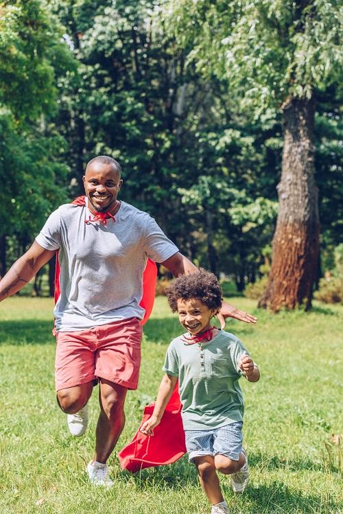 African American man playing in the park with his small son.